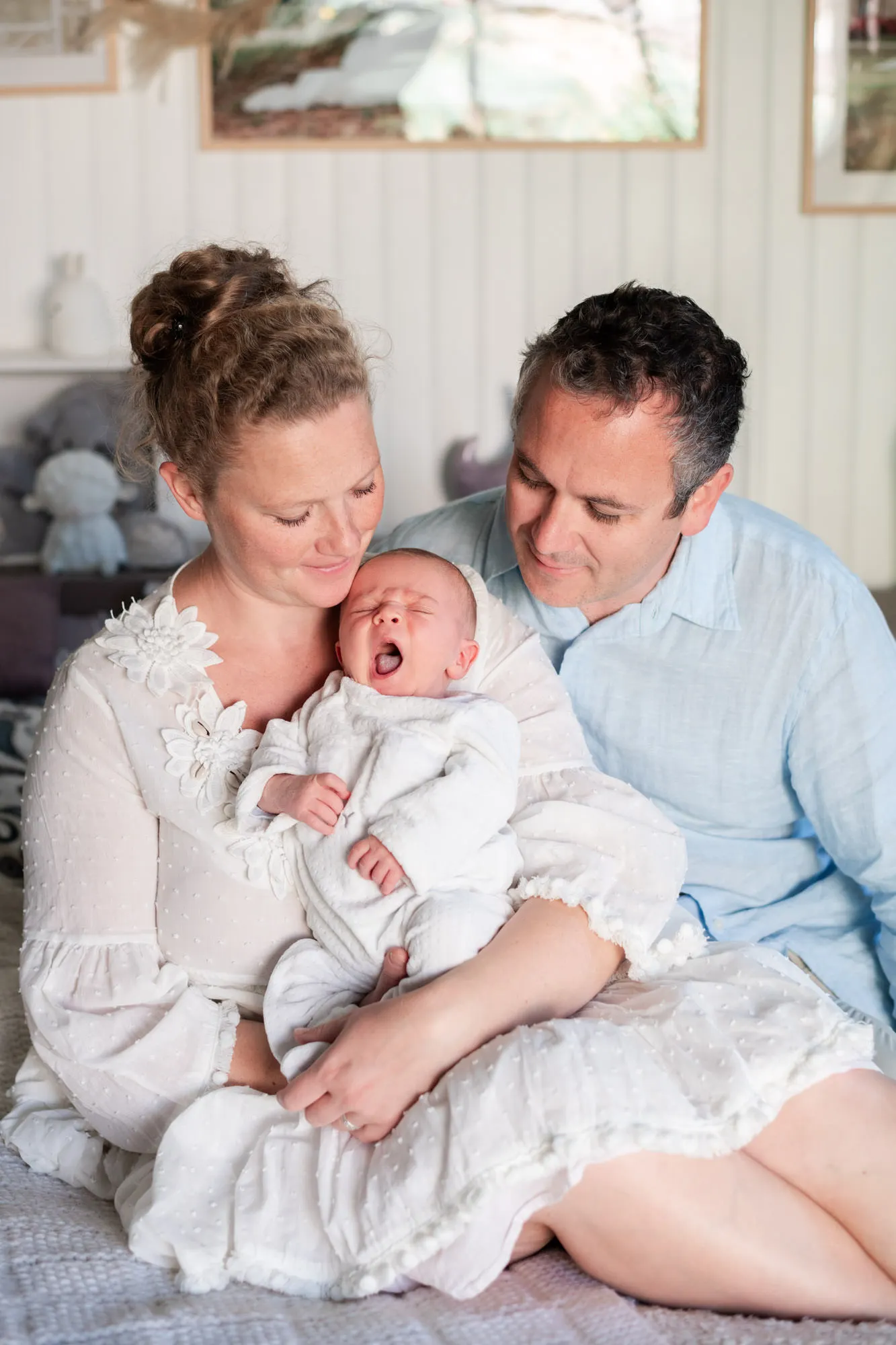 Portrait de famille de parents et leur nouveau-né qui baille lors de sa séance photo de naissance à domicile à Héricy à côté de Fontainebleau