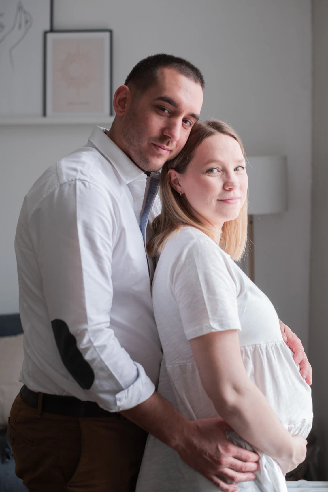 Femme enceinte de jumeaux et son mari, lors d'une séance photo de grossesse à domicile, dans leur salon près de Fontainebleau