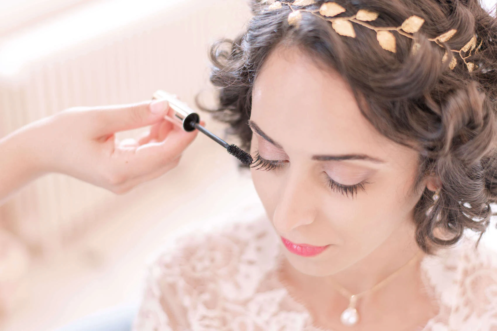 Photo d'une mariée lors de sa préparation de mariage, en train de se faire maquiller