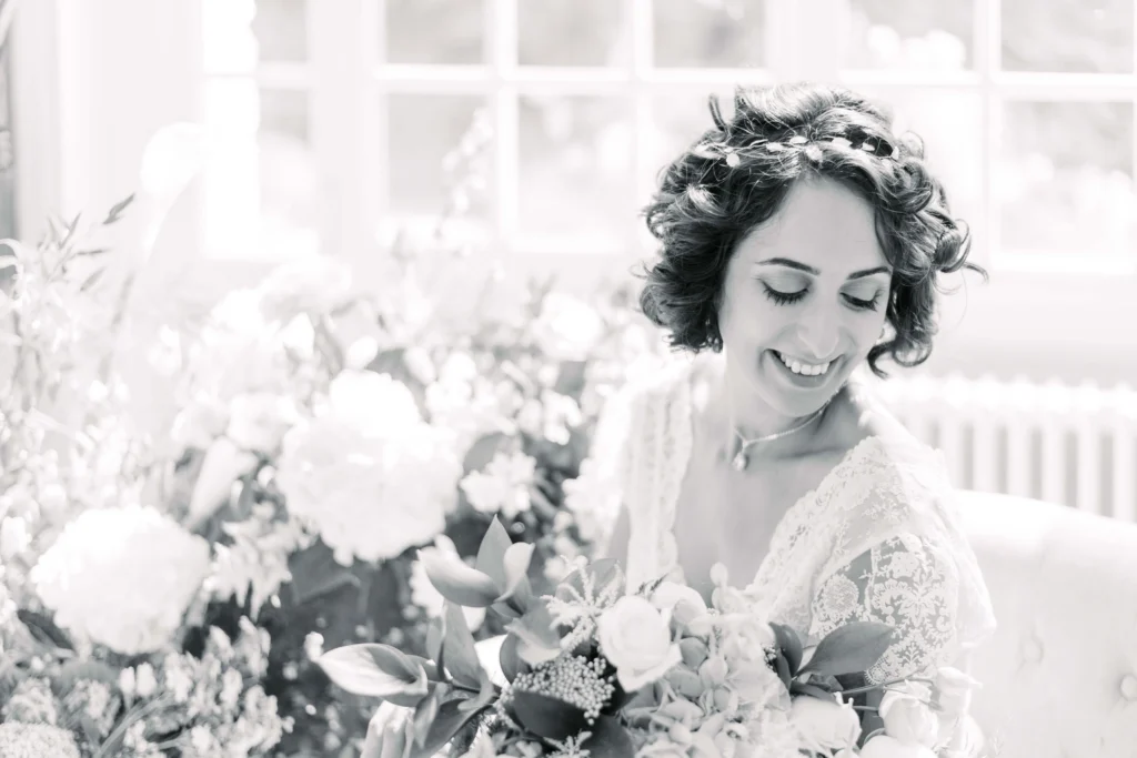 Photo en noir et blanc d'une mariée souriante, son bouquet à la main