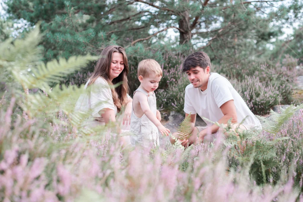 Moment de jeu en famille entre un papa, une maman et leur fils de 2 ans lors d'une séance photo en famille en forêt de Fontainebleau