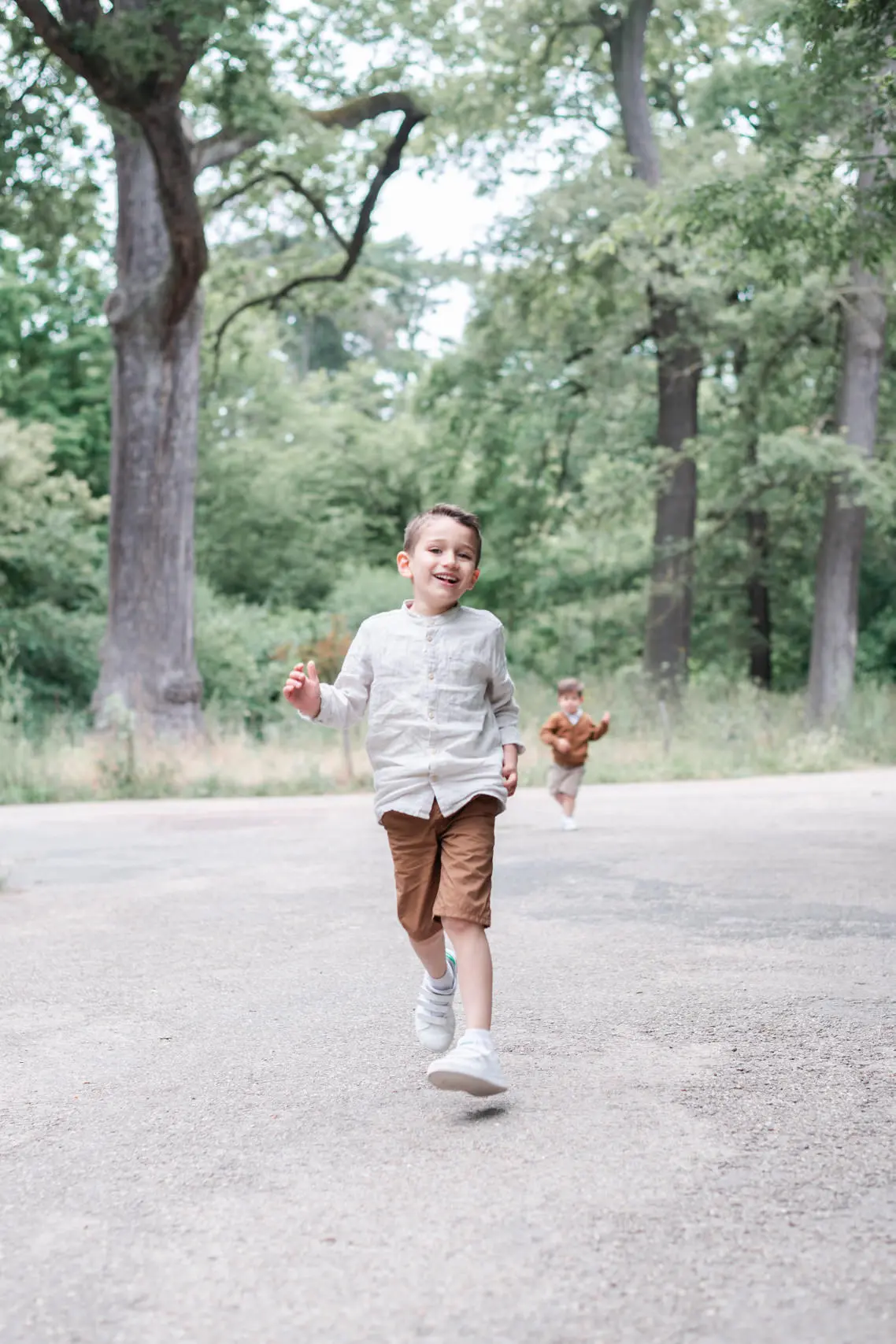 Photo de 2 enfants qui jouent et courent lors de leur séance photo en famille en extérieur en pleine nature