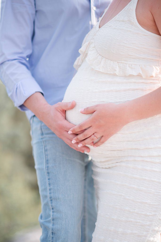 gros plan sur les mains d'un futur papa et d'une future maman sur le ventre de la femme enceinte, lors de leur shooting photo grossesse dans les gorges d'apremont