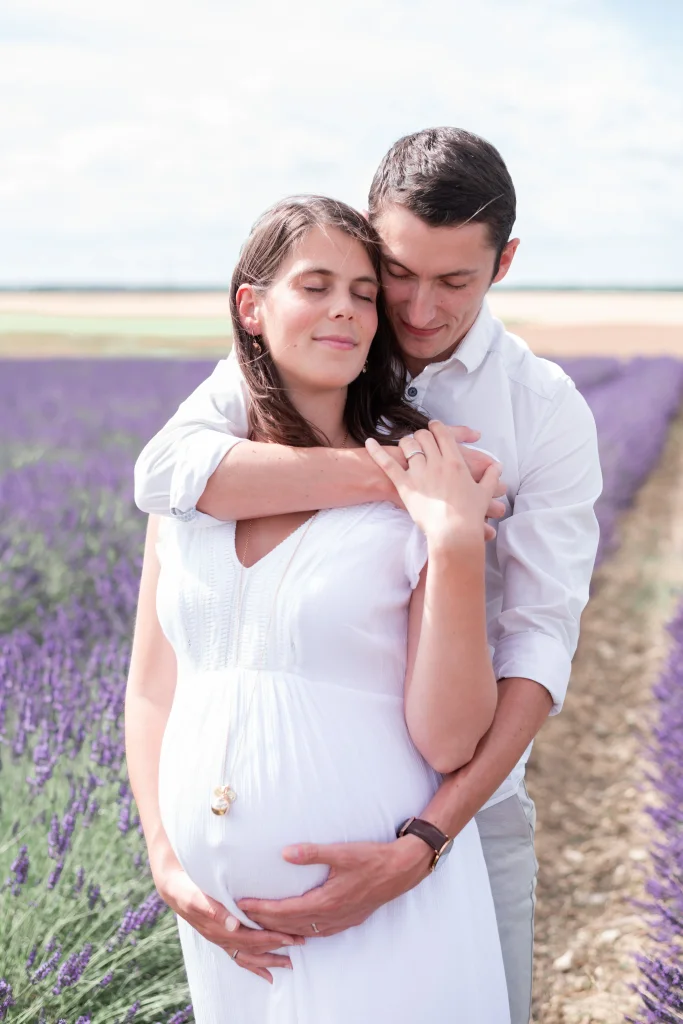 couple avec femme enceinte dans les champs de lavande lors de la séance photo de grossesse