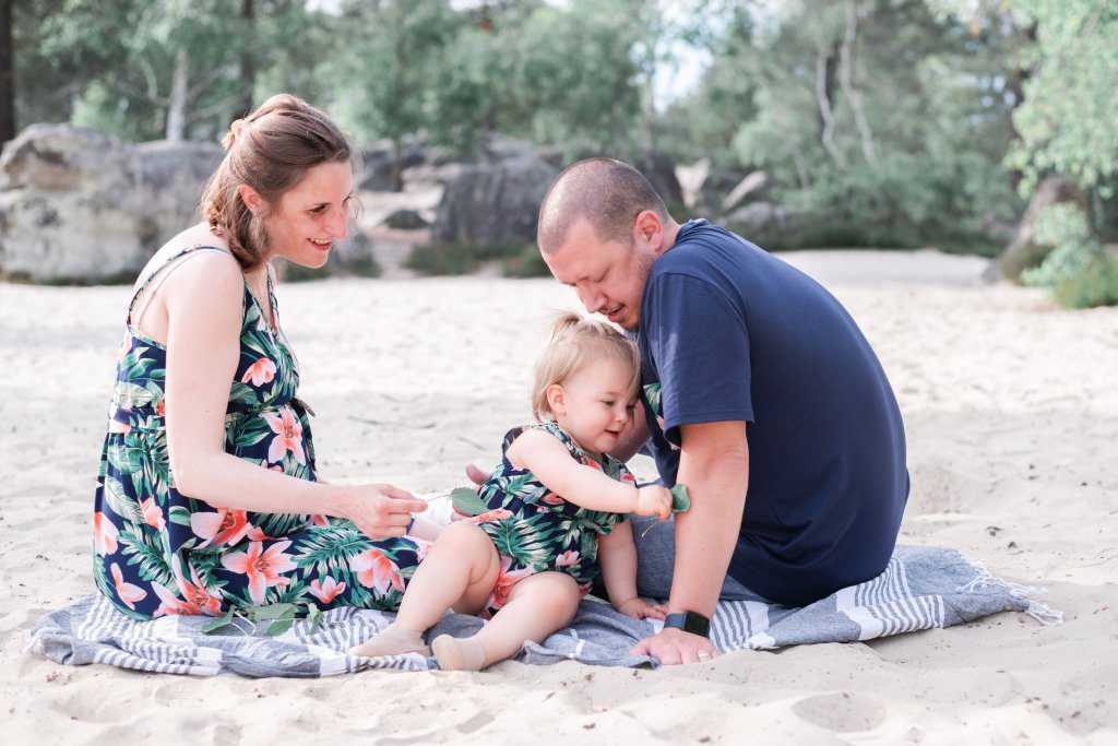 famille assis sur le sable aux Sables du cul de chien lors d'une séance photo de grossesse au printemps