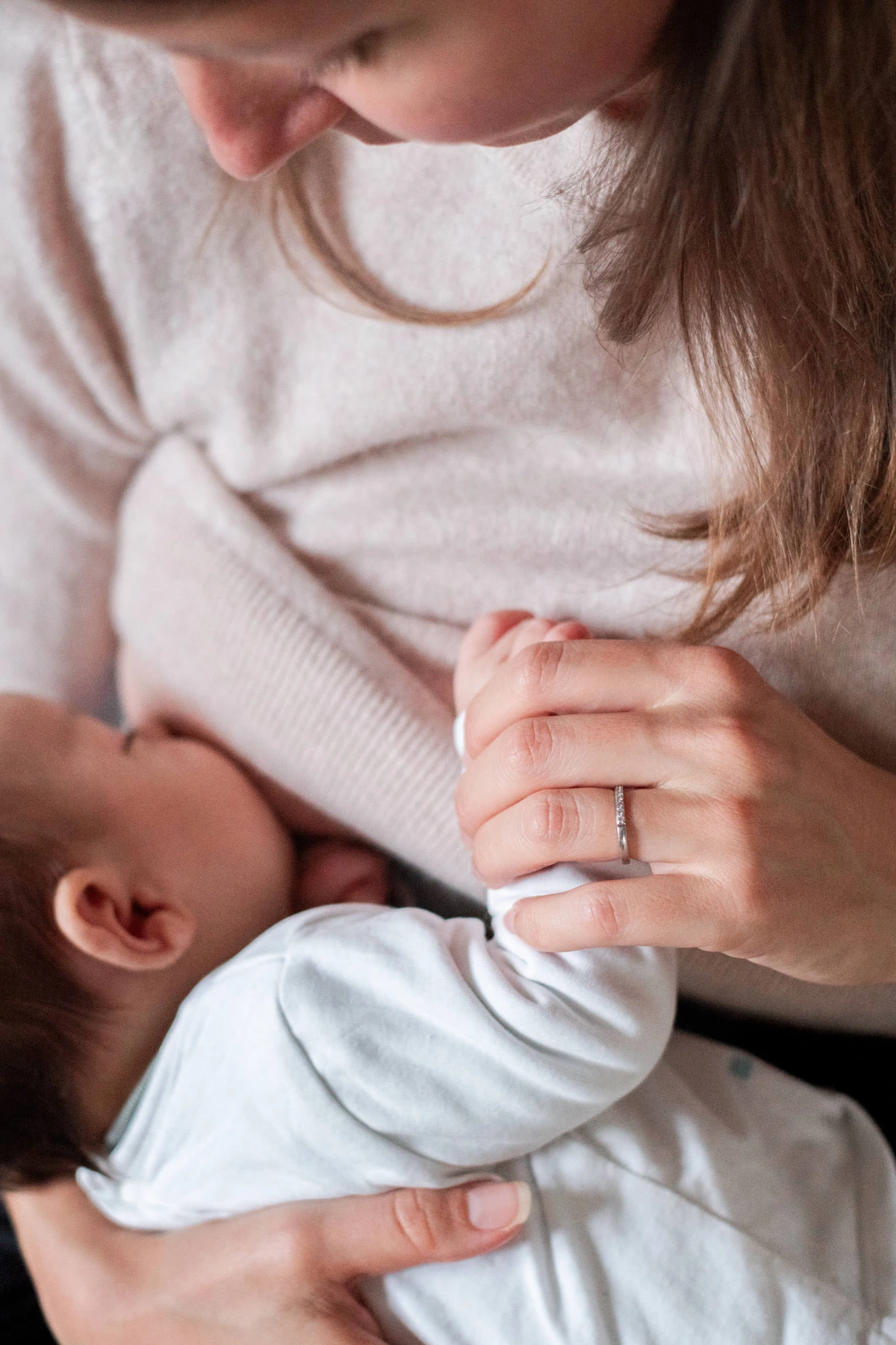 Gros plan sur la main d'une maman, tenant la main de son bébé lors d'une tétée réalisée pendant une séance photo allaitement près de Melun