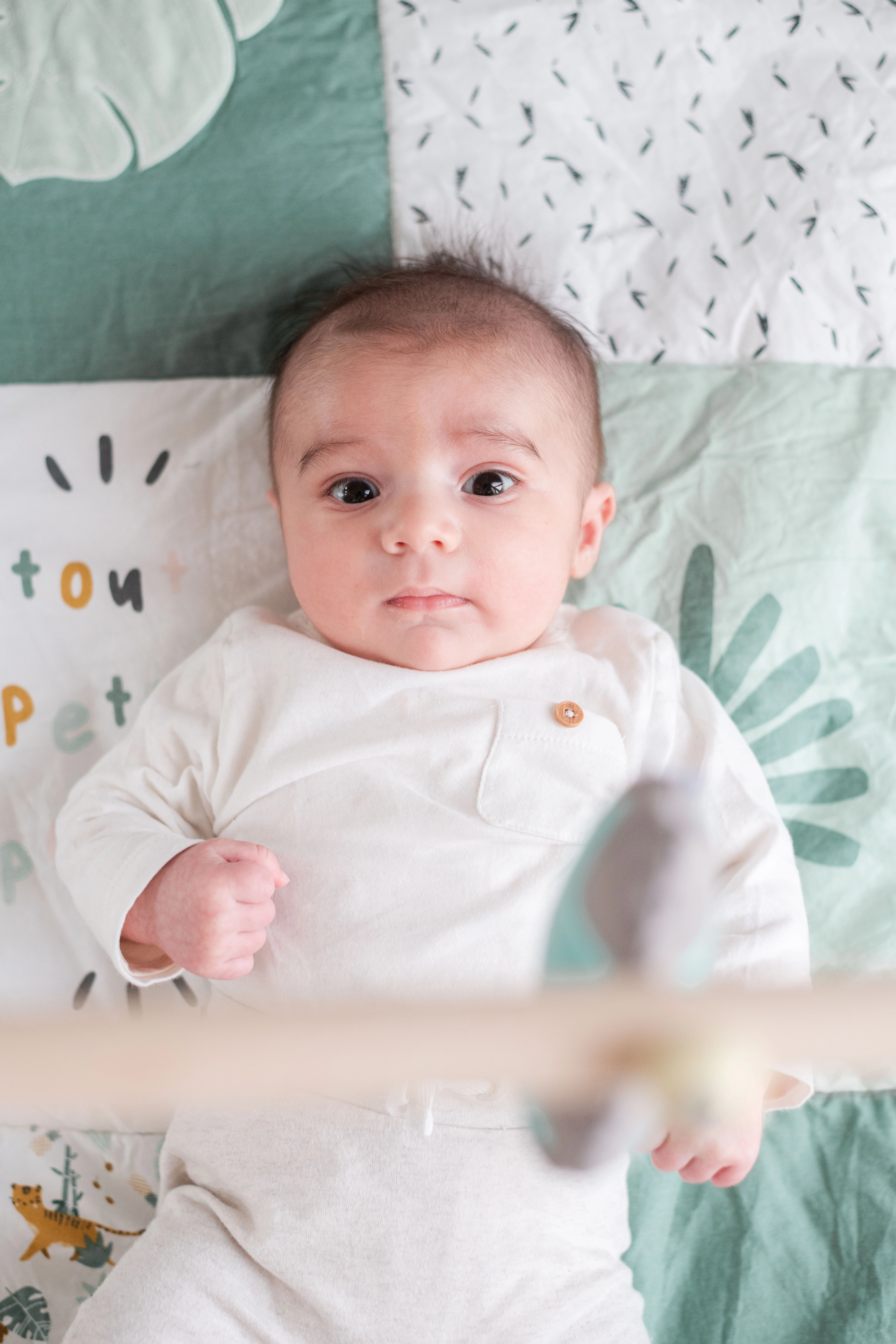 Portrait d'un bébé allongé sur son tapis d'éveil lors d'une séance photo bébé à domicile à côté de Melun