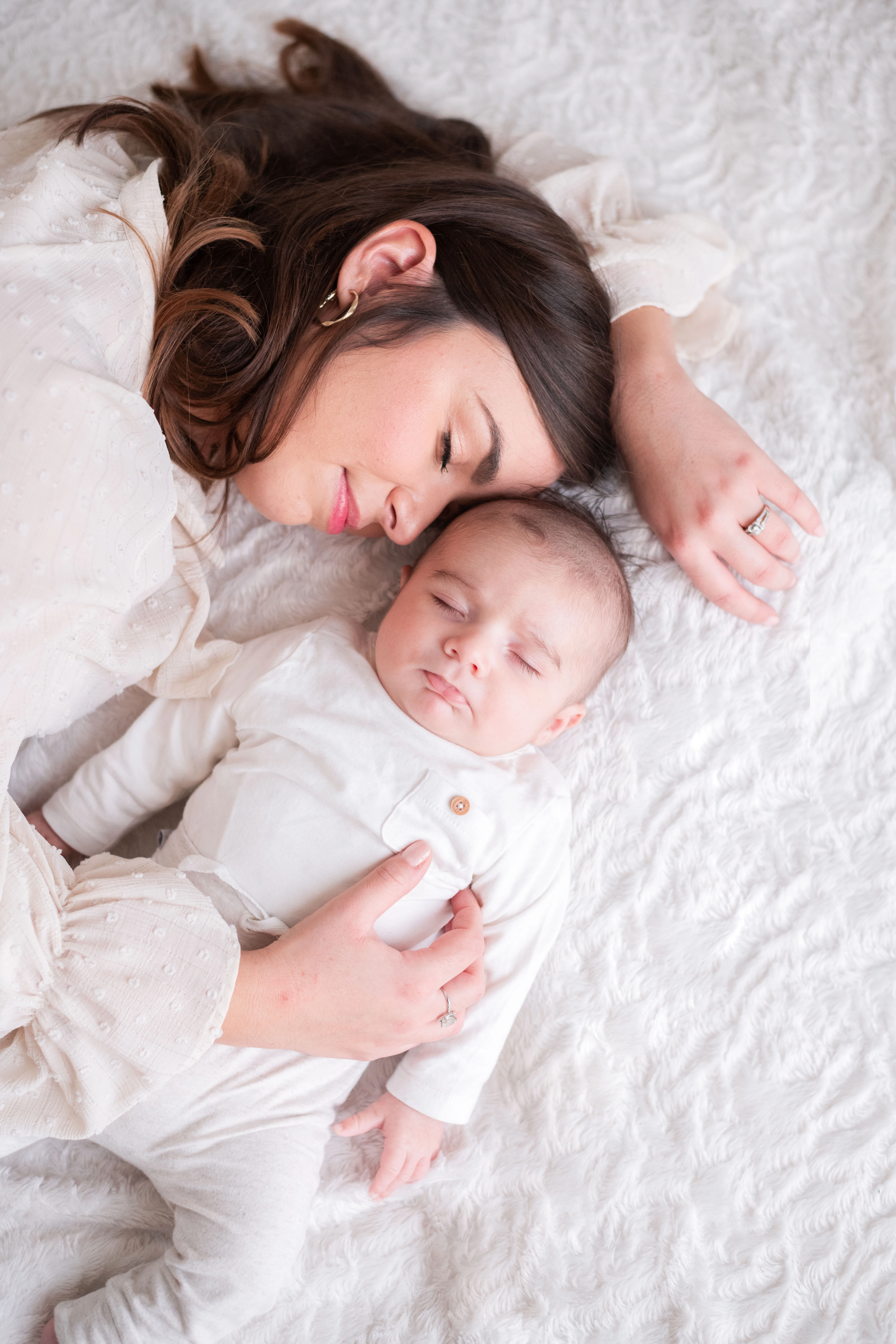 Portrait d'un bébé et sa maman allongés, endormis, blottis dans les bras l'un de l'autre, lors d'une séance photo à domicile à Melun